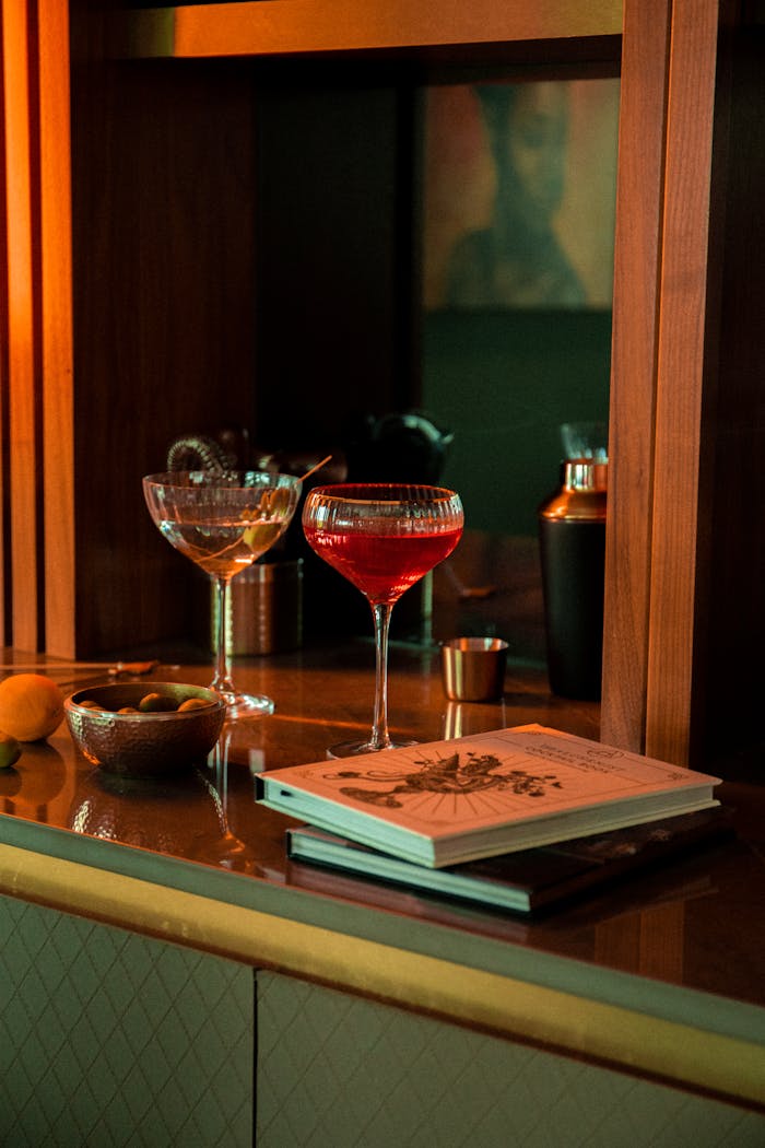A stylish bar scene with red cocktail, glasses, books, and decor.