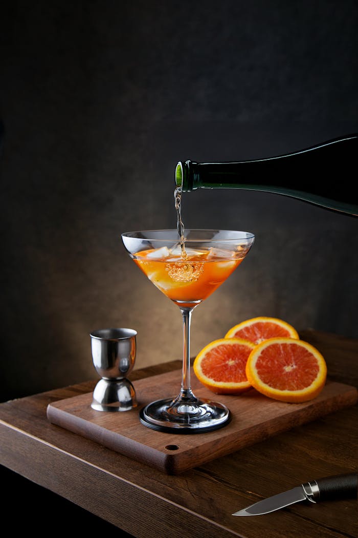 Elegant cocktail glass with orange slices and a knife on a wooden table. Perfect for bar promotion.