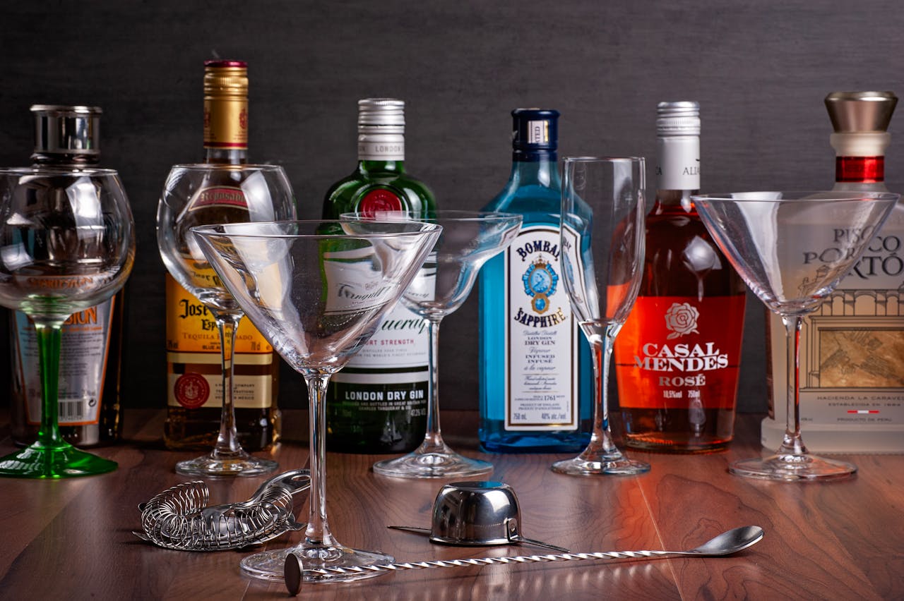 Assorted liquor bottles with cocktail glasses on a wooden surface - perfect for bar themes.